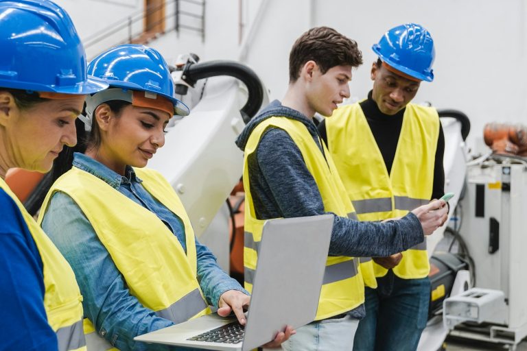 Multiracial industrial engineers working at automated AI robotic production factory - New tech