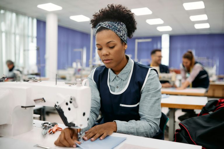 Young black seamstress working at textile factory.