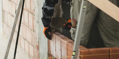 Bricklayer installing brick masonry on interior wall.