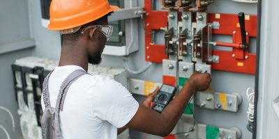 Electrician checking voltage in switchgear at solar station